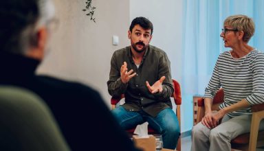 Diverse people discussing mental health problems on group therapy meeting. Recovering addicts getting psychologist and community support while telling they own story on rehab session. Focus on a man.